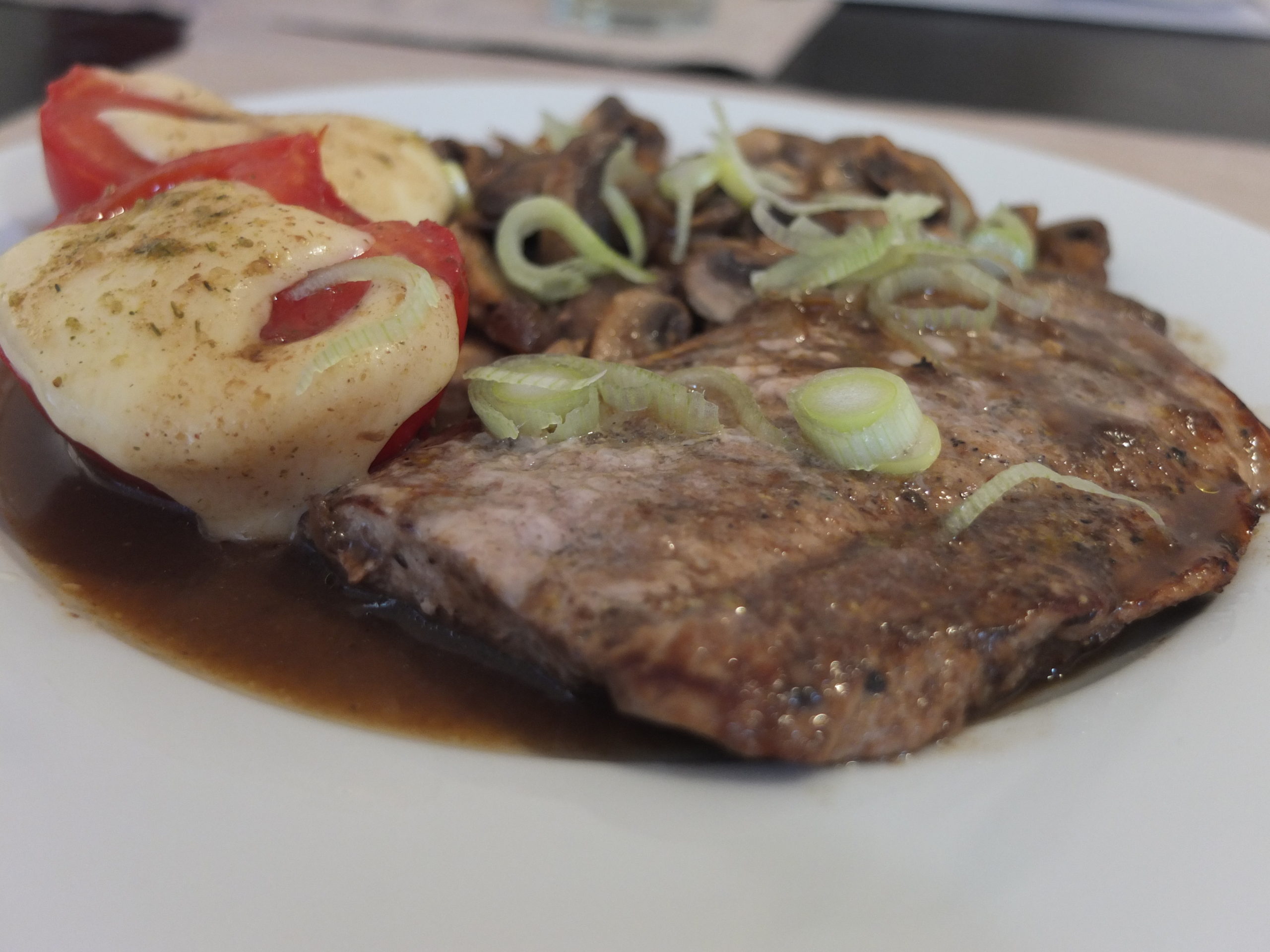 Schweinesteak mit überbackener Tomate und Pilzen